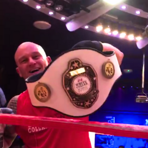 Luke holding up his championship belt after victory